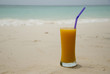 Glass with juice on the tropical beach with a sea and sand as a