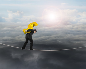 Poster - Businessman carrying golden dollar sign balancing on tightrope