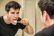 © theartofphoto - Headshot of attractive young man brushing teeth and tongue