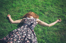 Young Woman Lying In The Grass On A Summer Day
