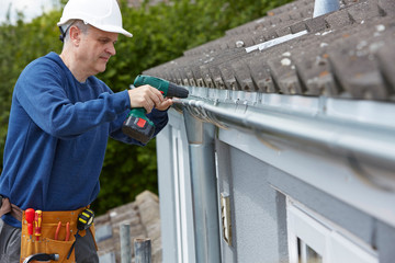 Workman Replacing Guttering On Exterior Of House