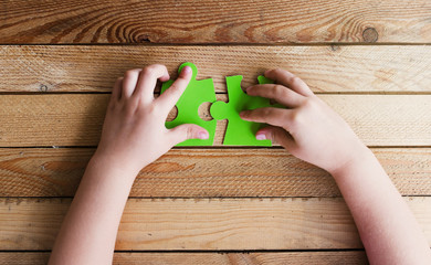 cropped image of hands connecting two puzzle pieces on wooden ta