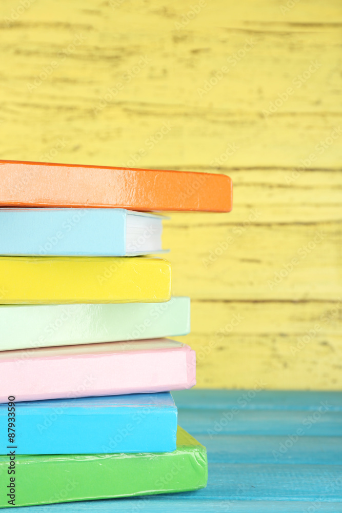 Colorful books on yellow wooden background