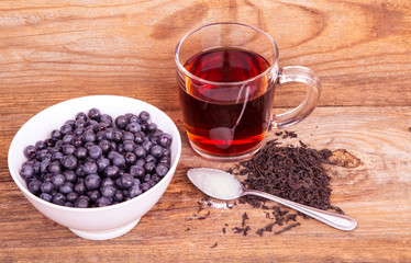 cup of tea and sweet blueberry in white bowl on a wooden backgro