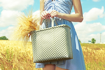 Canvas Print - Woman holding bag with sheaf outdoors