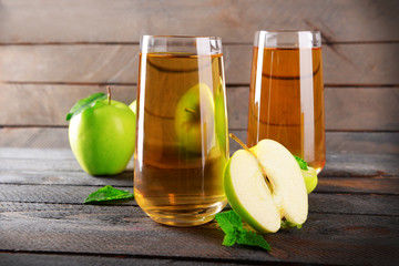 Glasses of apple juice on wooden background