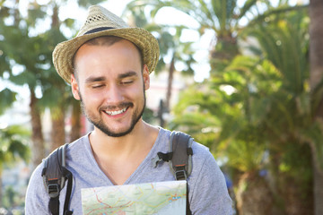 Wall Mural - Smiling young traveling man looking at map