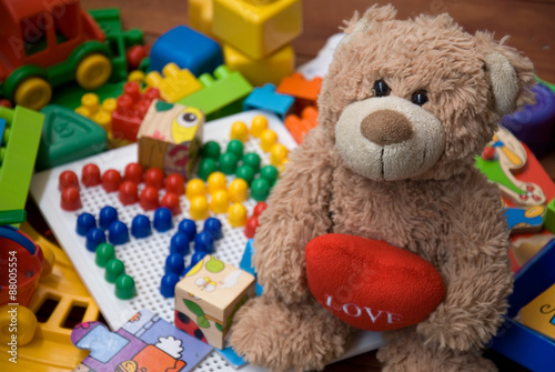 Obraz Dibond teddy bear surrounded by plastic toys