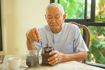 Asian senior man with vintage coffee grinder