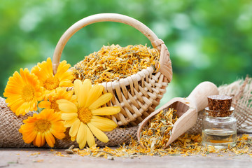 Wall Mural - Marigold flowers, basket with dried plants and bottles of essent