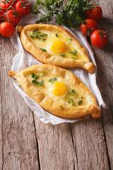 two khachapuri and fresh vegetables close-up on the table. vertical
