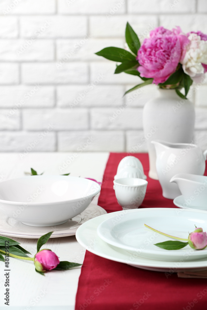 Beautiful table setting with flowers in vase on brick wall background