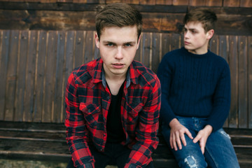 two men sitting on a wooden bench