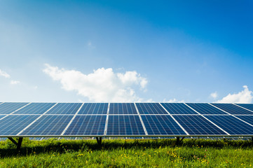 Solar panels on green field and blue sky