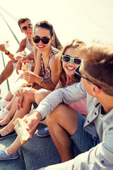 Wall Mural - group of smiling friends sitting on city square