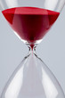 Red sand in an hourglass, vertical