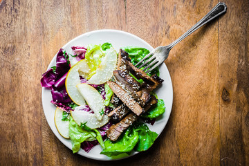 Wall Mural - Sliced meat steak with green salad and pears