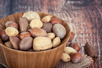 Mix nuts in a wooden bowl against rustic background