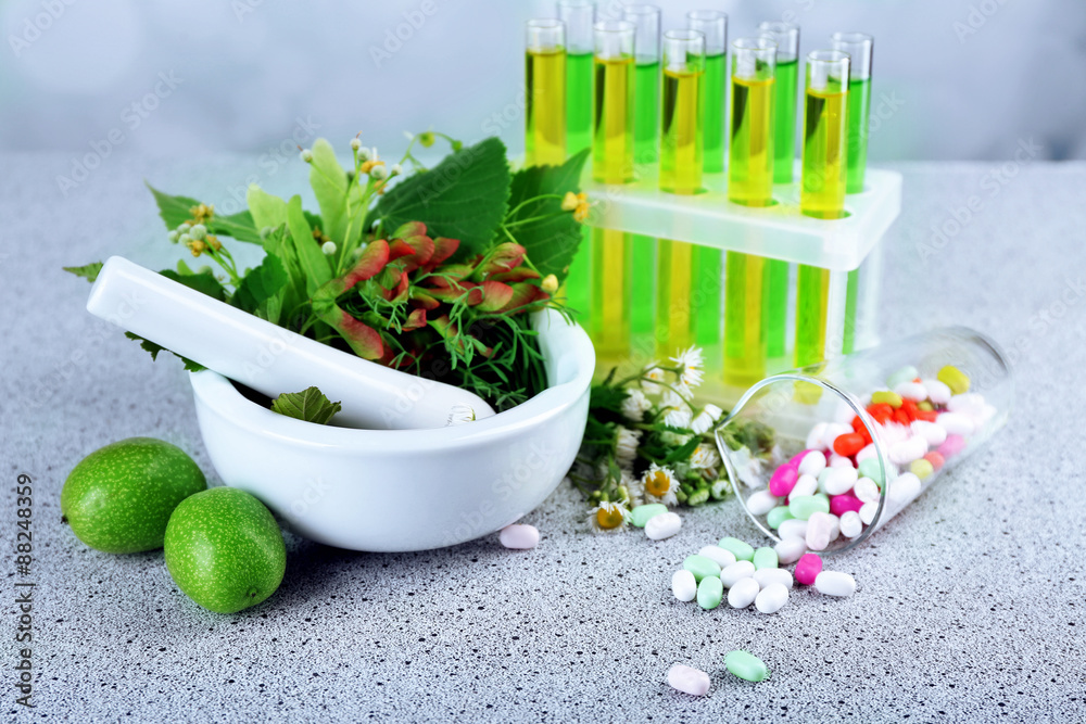 Herbs in mortar, test tubes and pills,  on table, on light background