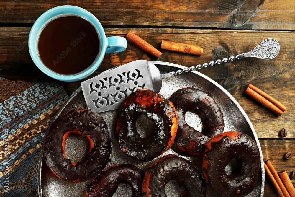 Delicious doughnuts with chocolate icing and cup of coffee on table close up