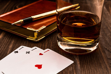 Wall Mural - Glass of whiskey and playing cards with leather notebook on a wooden table