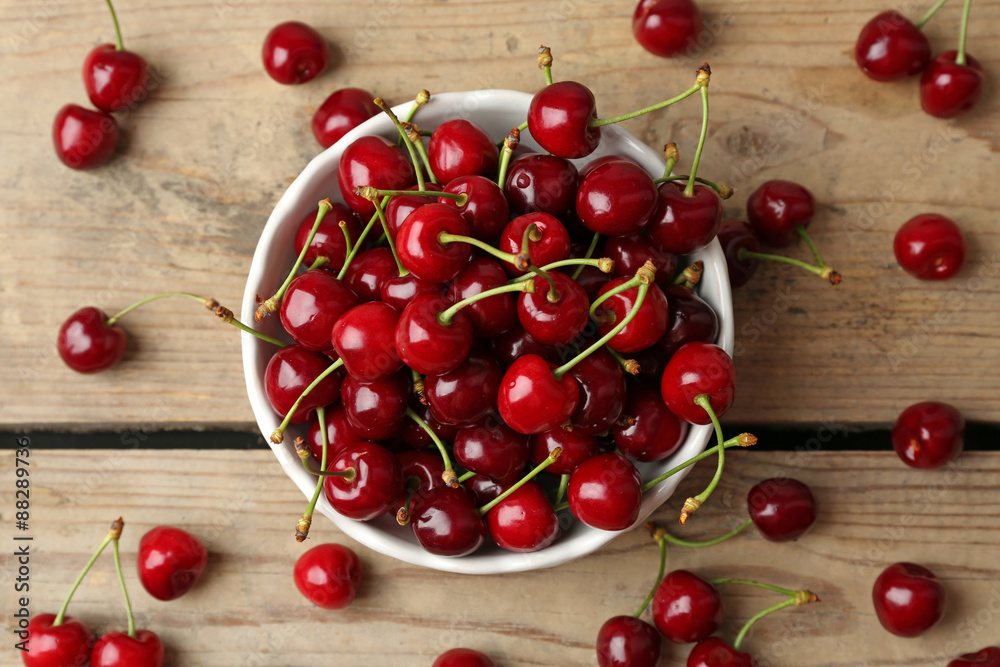 Sweet cherries in bowl on wooden table close up