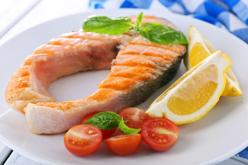 Wall Mural - Tasty grilled salmon with tomato and lemon on table close up