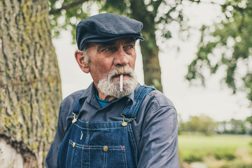 Wall Mural - Senior country farmer standing smoking