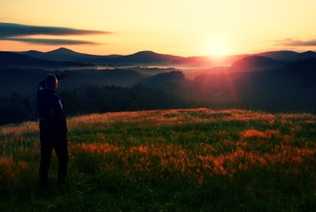 Wall Mural - Meadow colorful sunrise with dark  man silhouette