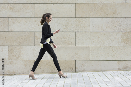 Fotografía Businesswoman looking at phone while walking.
