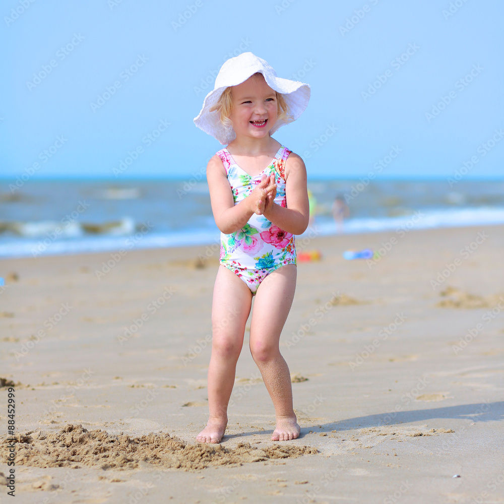 kids girl on the beach Cute active child wearing white hat playing on sandy beach. Happy little  girl enjoying summer holidays on a sunny day. Family with young kids on  vacation at the North Sea coast. の