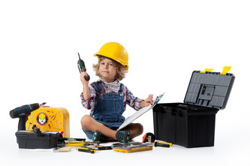 Little boy dressed as utility worker with protective helmet trying to figure ou how the drill works