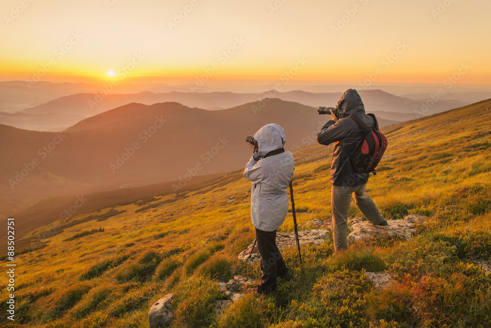 Photographers takes a sunset in the mountains - obrazy, fototapety, plakaty 