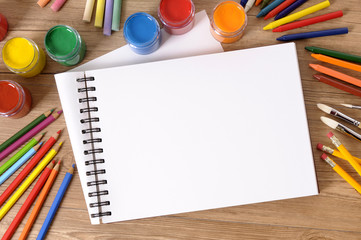 Canvas Print - Open book blank white on a school student desk with pencils crayons and paint art and craft lesson photo