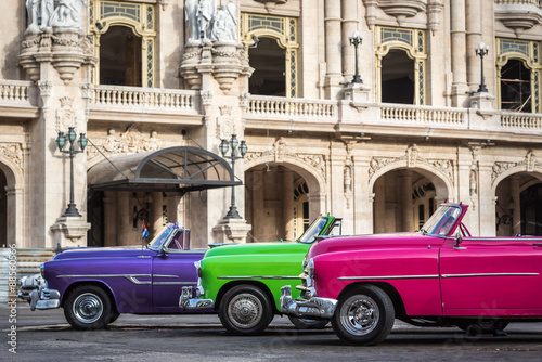 Fototapeta na wymiar Kuba drei farbenfrohe amerikanische Oldtimer parken in Reihe vor dem Gran Teatro in Havanna