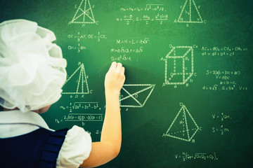 Smart student or schoolgirl drawing mathematic formula at blackboard