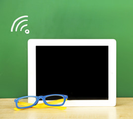 Canvas Print - Tablet on table, on green blackboard background