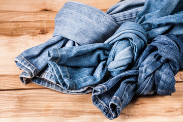 Sticker - fashionable clothes. pile of jeans on a wooden background