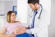 © WavebreakMediaMicro - Doctor examining stomach of pregnant patient and giving advice