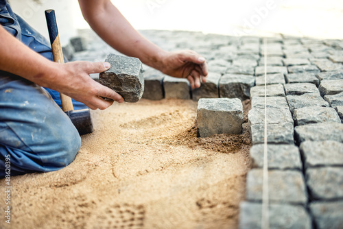 Cuadros en Lienzo construction worker placing stone tiles in sand for pavement, terrace