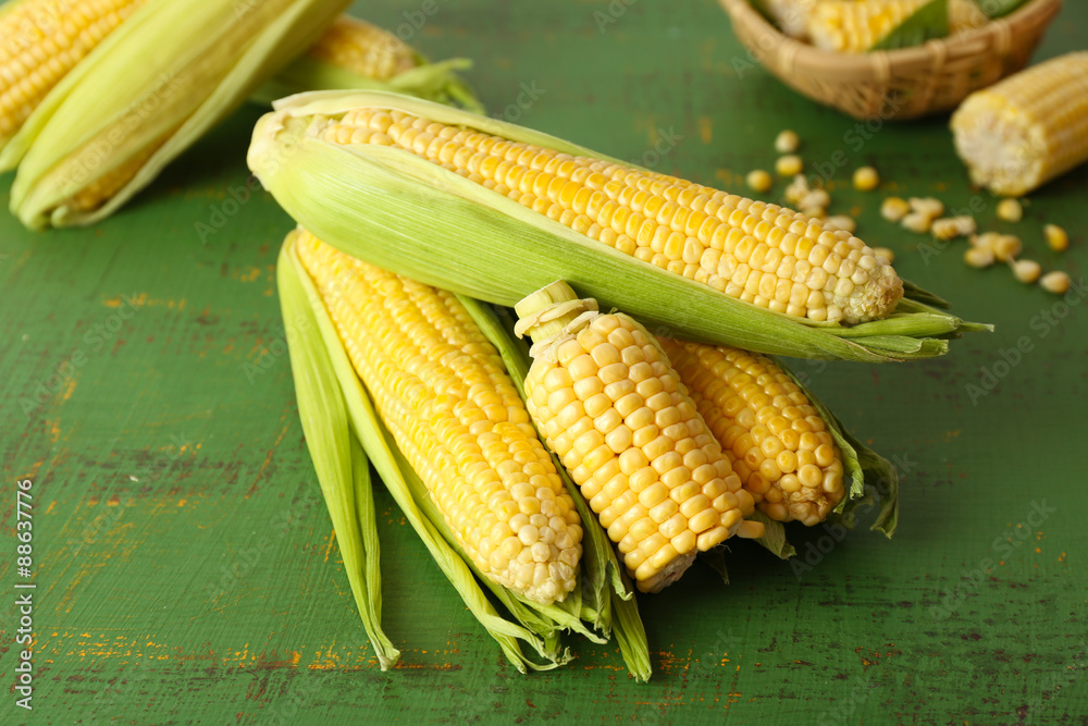 Fresh corn on cobs on green wooden background