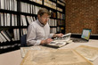 Researcher in Archive Examining Maps and Other Archival Material