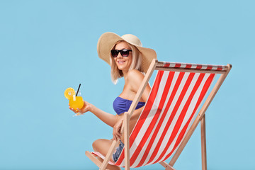 Poster - Woman sitting in a sun lounger and holding a cocktail