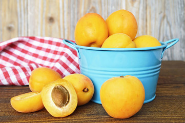 Wall Mural - Fresh sweet apricots in a blue metal bowl on wooden background                             