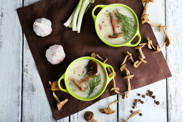 Mushroom soup with greens on wooden table with napkin, top view