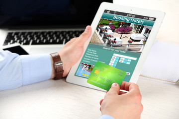 Poster - Man holding tablet with screen interface of booking hotels