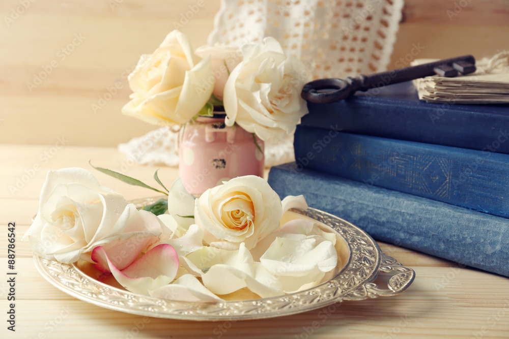 Fresh roses with old book, key and letters on wooden table background. Vintage concept