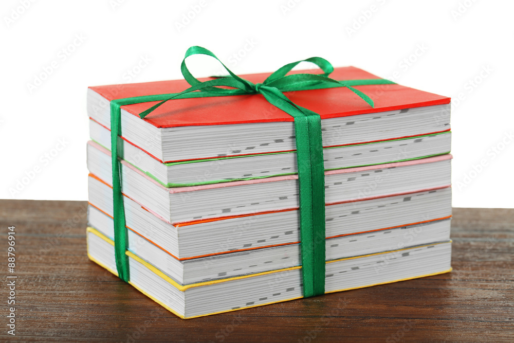 Stack of books with ribbon on light background