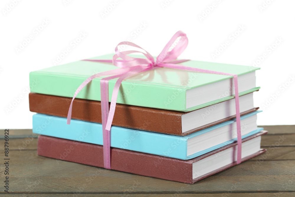Stack of books with ribbon on light background
