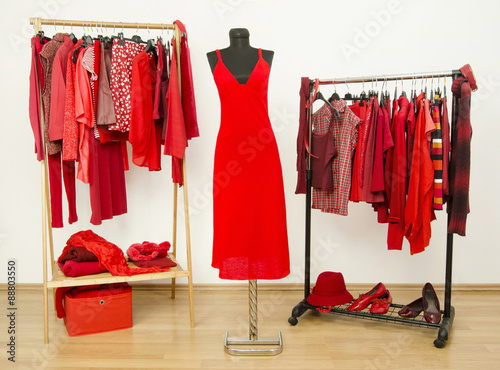 Dressing Closet With Red Clothes Arranged On Hangers And A Dress